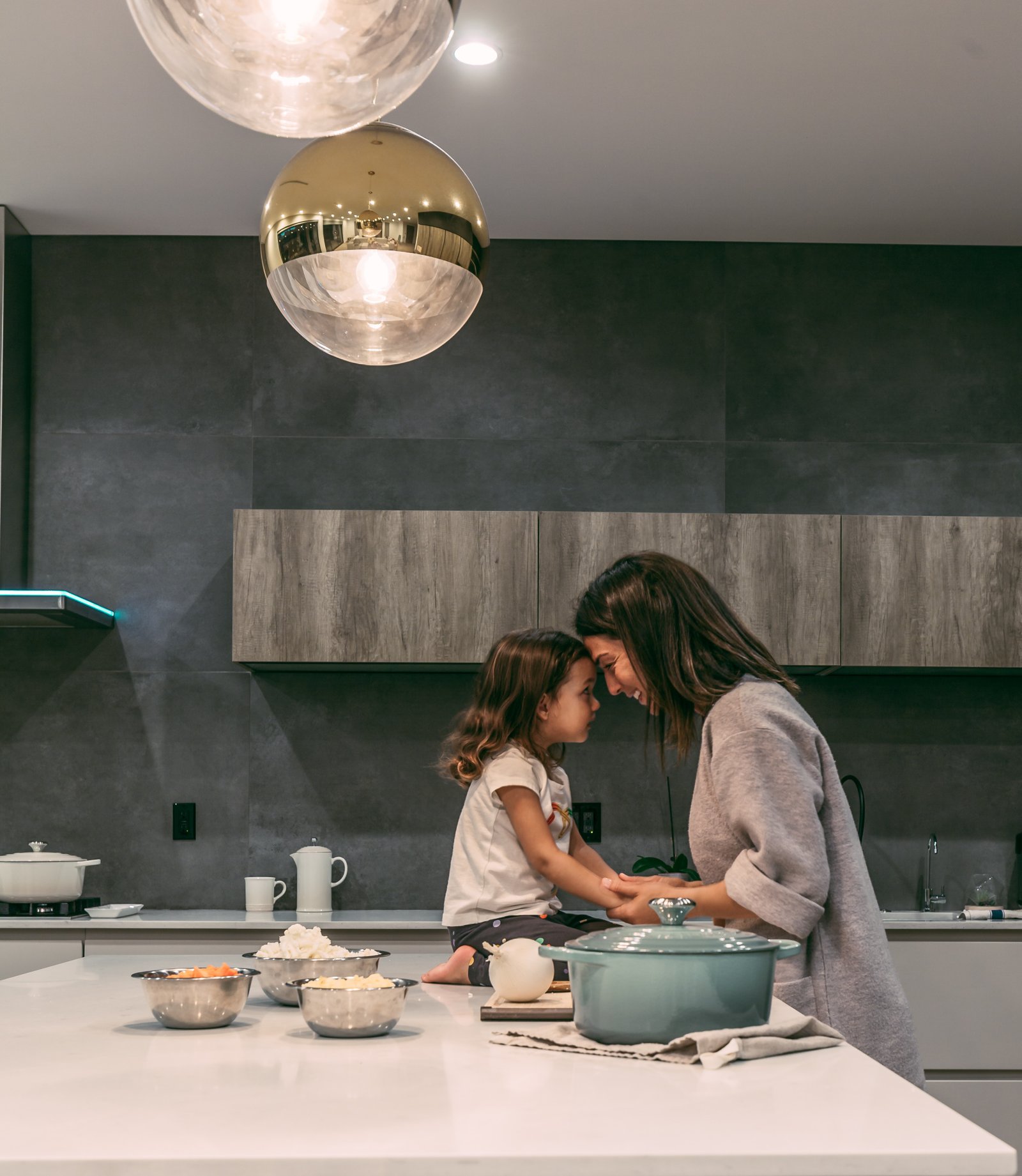 A mom snuggling with daughter in kitchen