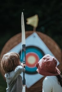 A mother teaches her son to shoot an arrow | Photo by Annie Spratt on Unsplash.