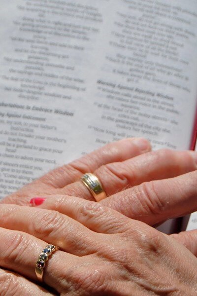 man wife hands on Bible
