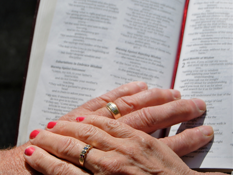 man wife hands on Bible